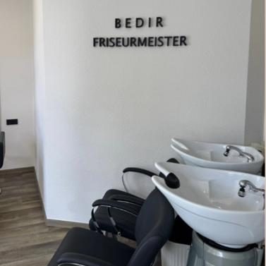 Platz für Veränderung Schwarzer Friseurstuhl vor einem Spiegel und einem weißen Beistelltisch.